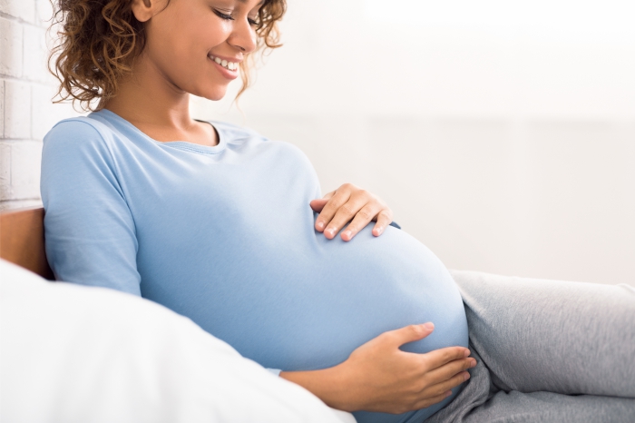 Gestante, mulher grávida relaxando no sofá após sessão de aromaterapia para gestantes.